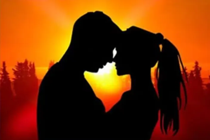 Silhouettes d'un couple front contre front au coucher du soleil