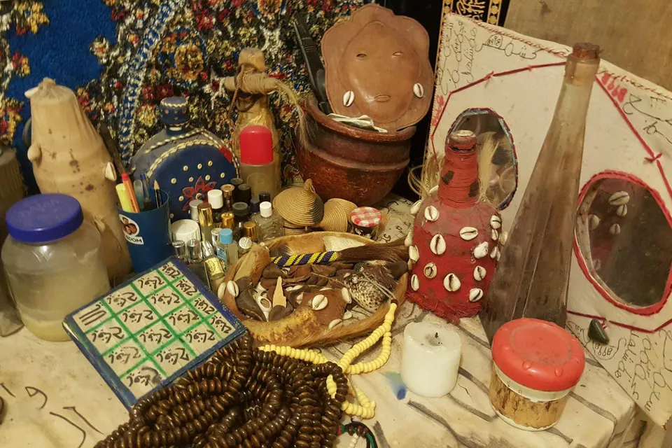 Table de travail d'un marabout : chapelets, bouteille ornée de cauris, écritures en arabe