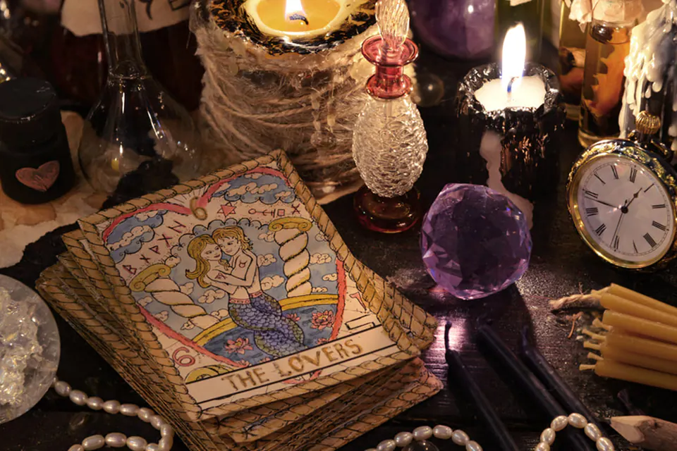 Cartes de tarot, bougies et montre à gousset sur une table