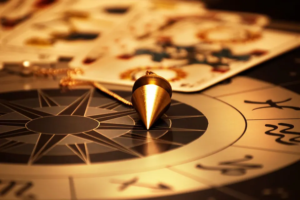 Pendule doré au-dessus d'une roue zodiacale et de cartes