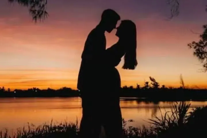 Couple enlacé à contre-jour au bord d'un lac, sous un ciel de crépuscule